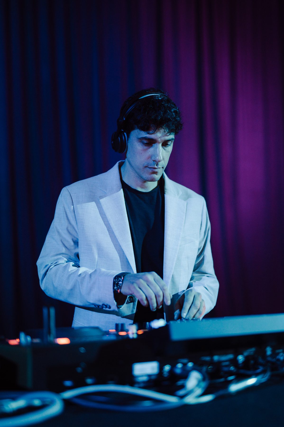 Jam Mattia in giacca chiara alla console durante una festa aziendale: DJ set per eventi corporate con luci viola