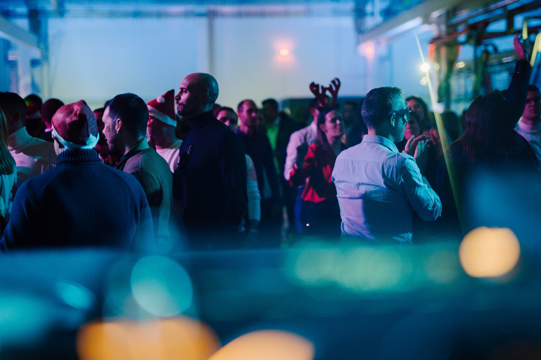 Pubblico di una festa aziendale sotto luci blu e verdi durante il DJ set di Jam Mattia