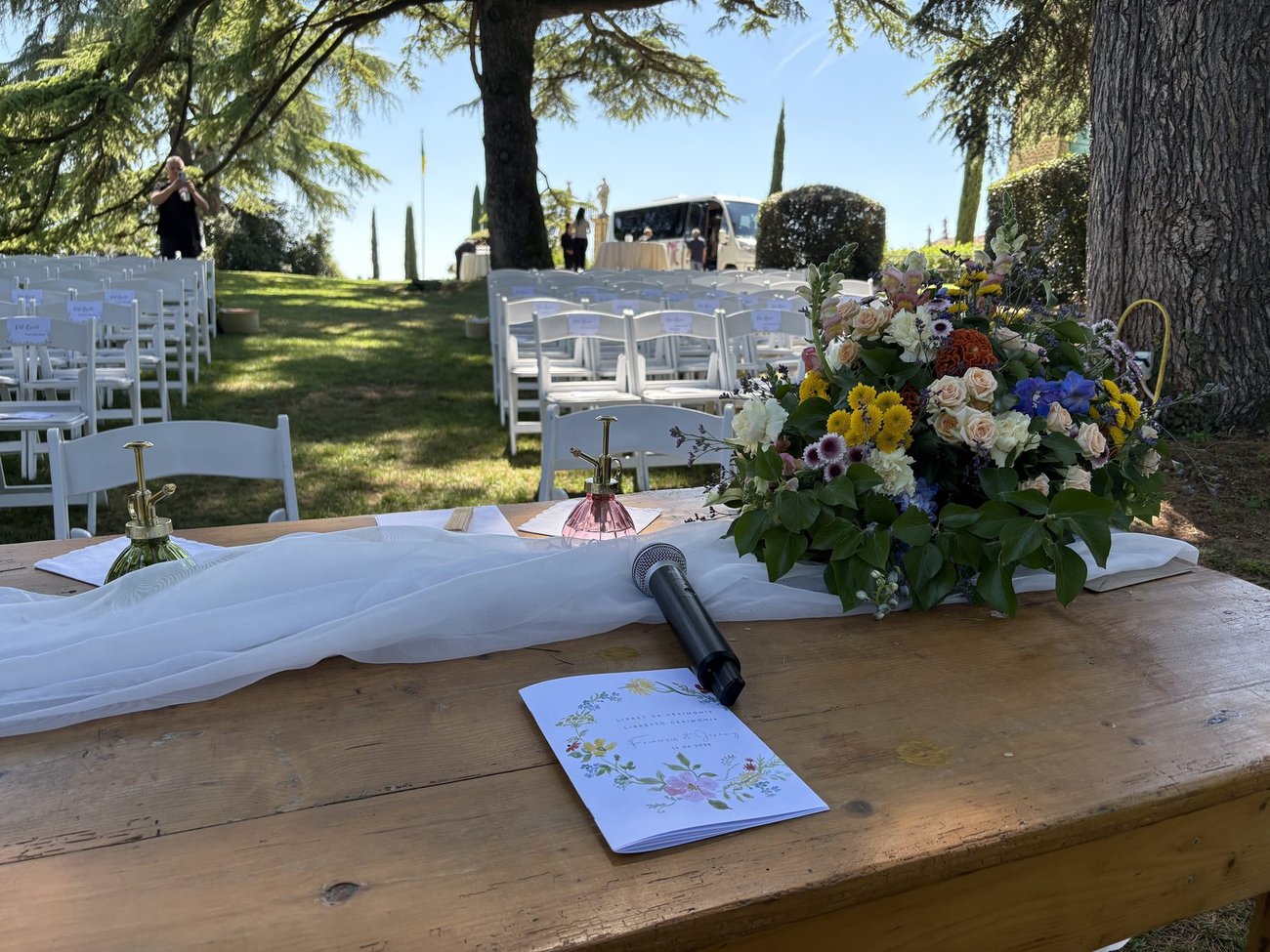 Setup audio per cerimonia di matrimonio all'aperto: tavolo del rito con fiori, microfono wireless a lungo raggio e impianto a batteria, perché la voce si senta bene in ogni punto del prato