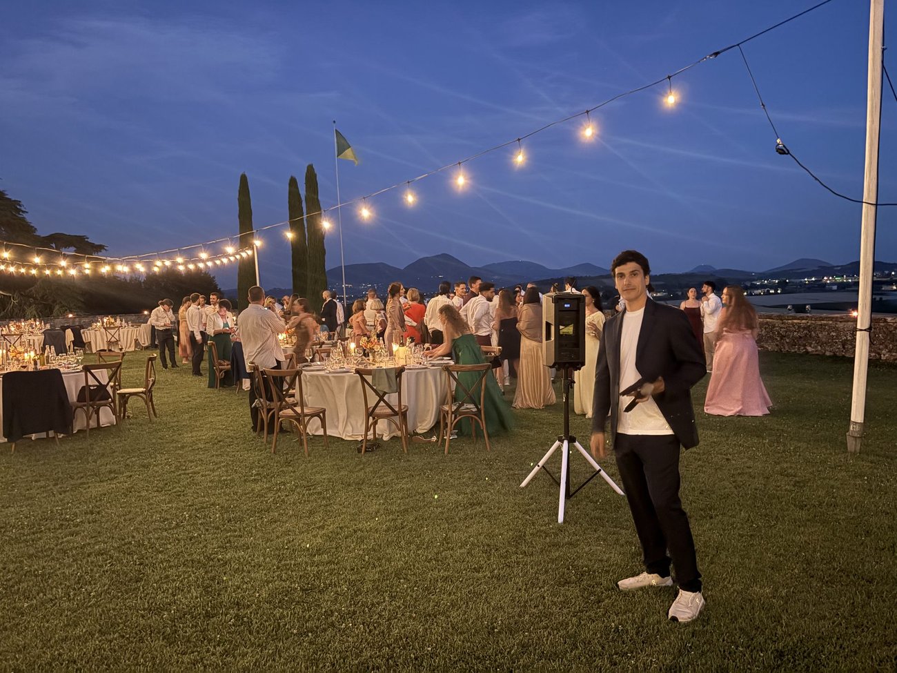 Matrimonio internazionale a Villa di Montruglio (Mossano, Vicenza): setup audio esterno completamente a batteria per la cena in giardino sotto le luci a filo, con microfono per i discorsi degli sposi e degli ospiti