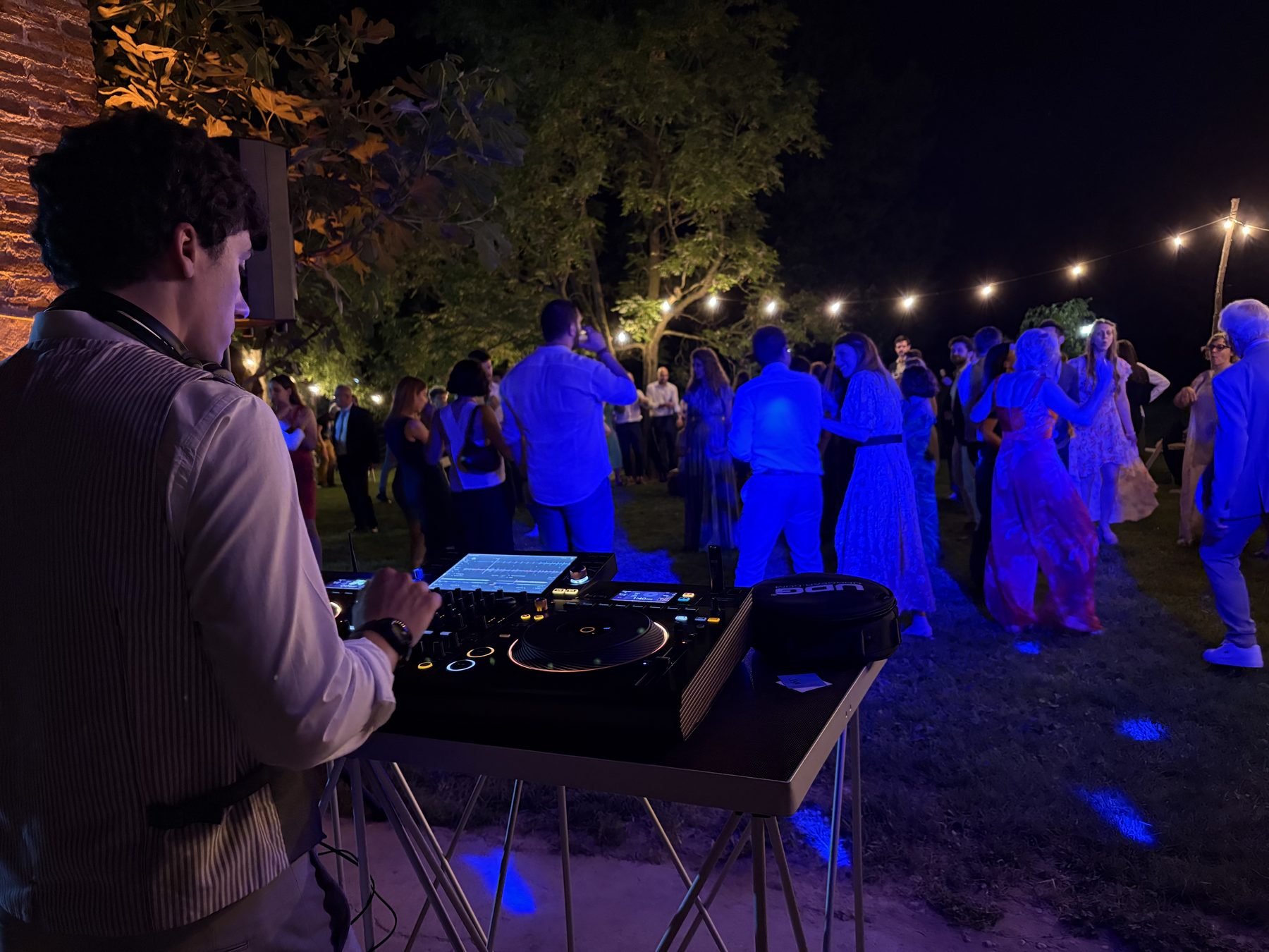 Setup DJ esterno in una villa privata a Padova: Jam Mattia alla console mentre gli ospiti ballano in giardino sotto luci blu e lampadine a filo