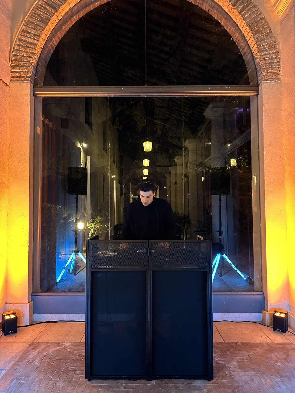 Setup interno completamente a batteria a Villa Solatia (Caldogno, Vicenza): postazione DJ sotto l'arco in mattoni con luci ambra, nessun cavo di alimentazione