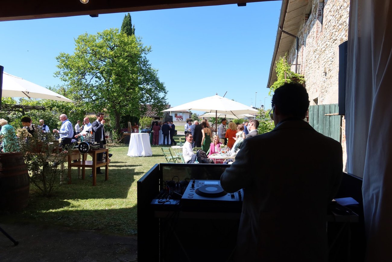 Aperitivo di matrimonio nel giardino di Borgo Garzolini (Buttrio, Udine): Jam Mattia alla console sotto il portico, ombrelloni e ospiti sul prato