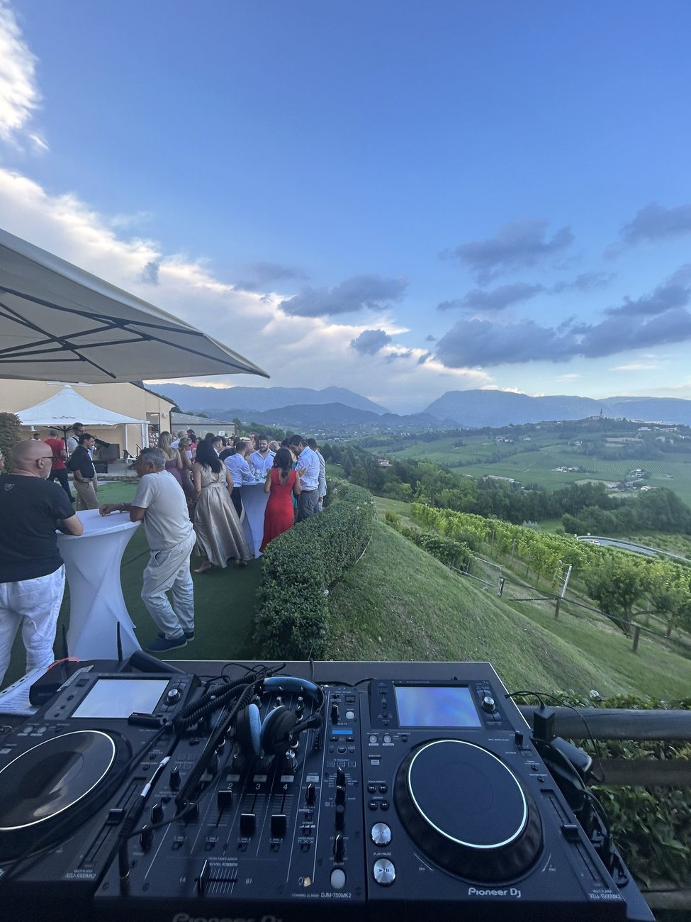 Setup DJ esterno professionale a Ca' del Poggio (San Pietro di Feletto, Treviso) tra le colline del Prosecco: console Pioneer con vista sui vigneti, la musica accompagna l'aperitivo di matrimonio degli ospiti sotto l'ombrellone