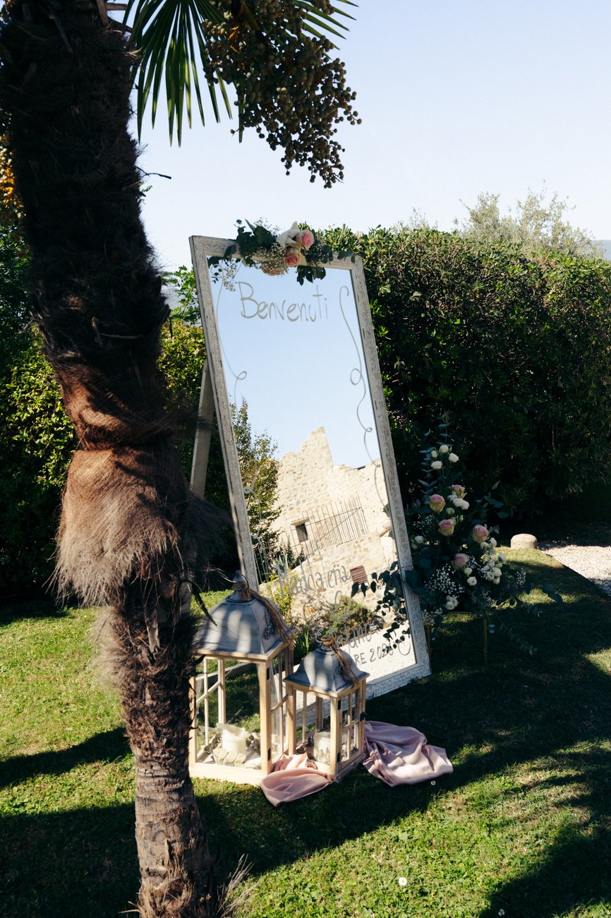 Specchio di benvenuto con fiori e lanterne nel giardino di Castelletto Eventi (Treviso), dettaglio dell'allestimento di un matrimonio con DJ Jam Mattia