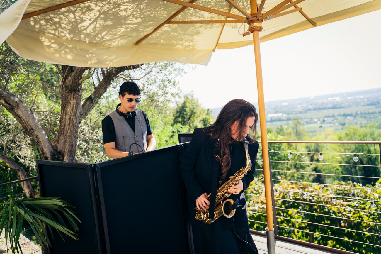 DJ set con sax dal vivo sotto l'ombrellone a Castelletto Eventi (Treviso): Jam Mattia alla console e la sassofonista accanto, momento di aperitivo curato ed elegante con vista sulla campagna