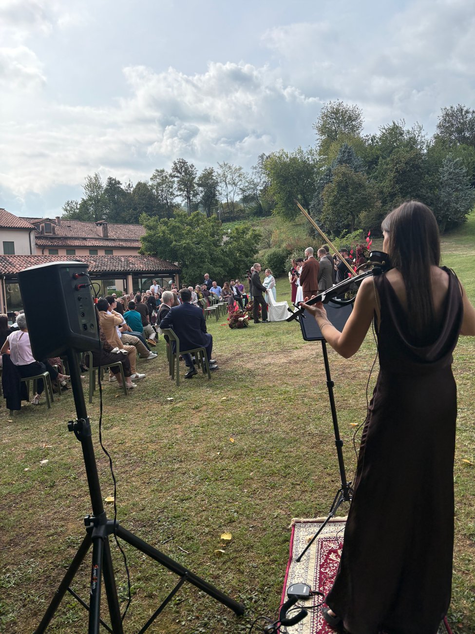Violinista dal vivo alla cerimonia di matrimonio della Locanda Perinella (Brogliano, Vicenza), cassa a batteria su stativo e invitati sul prato