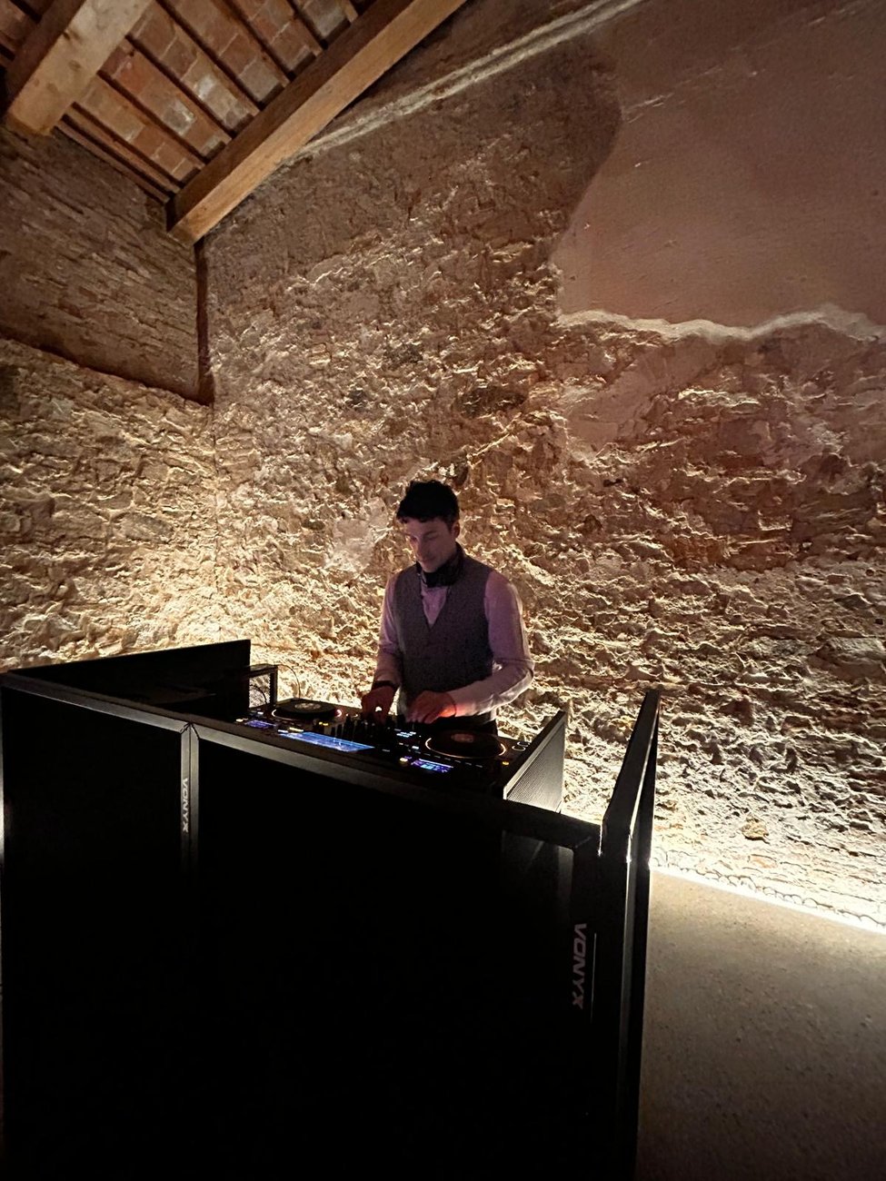 Postazione DJ nella sala in pietra di Villa Selvatico (Battaglia Terme, Padova) con luce calda radente sulle pareti, Jam Mattia alla console
